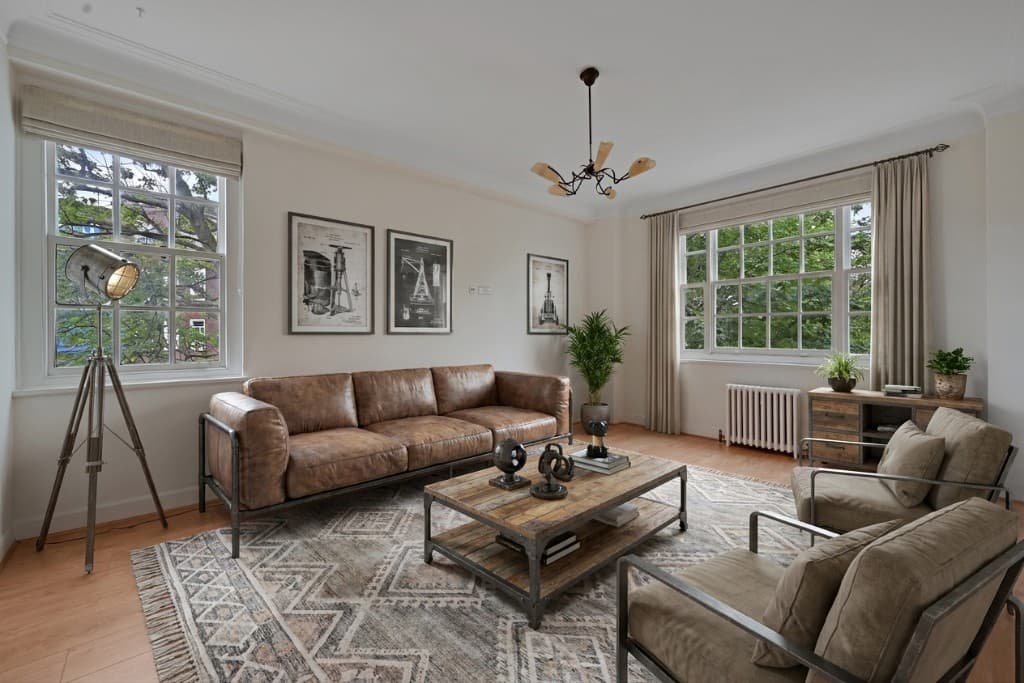 The same room virtually staged in an industrial style with leather sofa, metal-framed chairs and reclaimed wood table