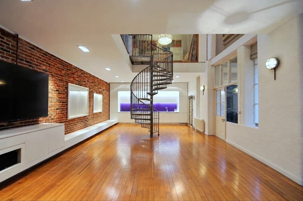 Empty open-plan loft with a spiral staircase before virtual staging