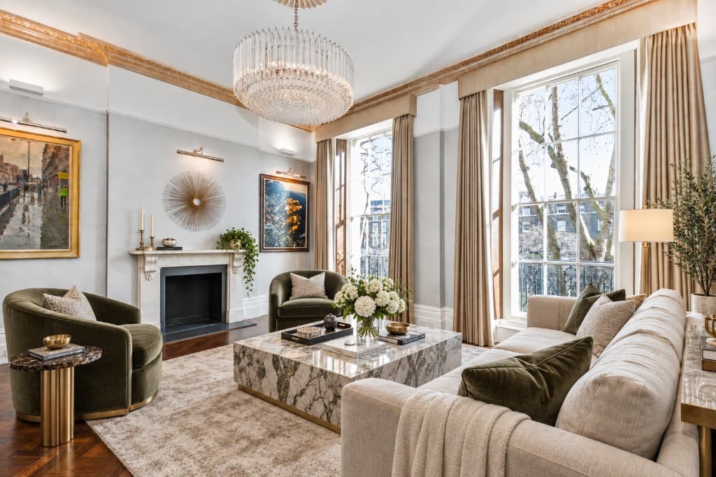 The same reception room virtually staged with a cream sofa, olive velvet chairs and a marble coffee table