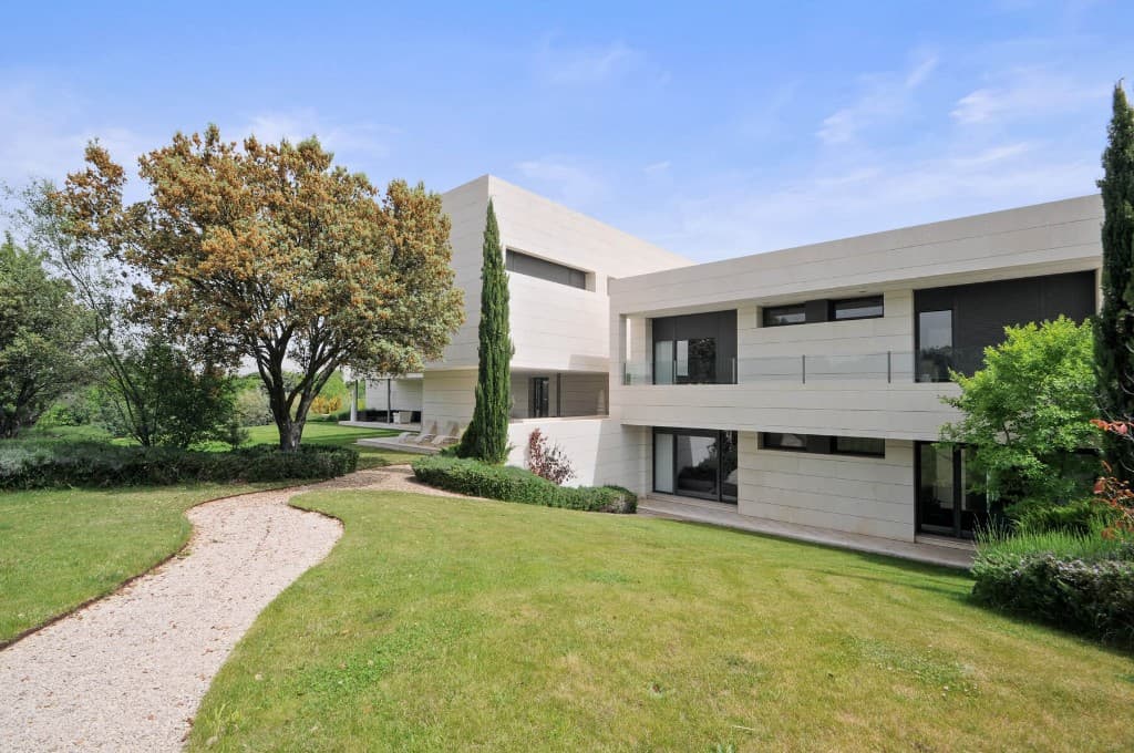 Modern stone house photographed in daytime with a pale blue sky and light cloud